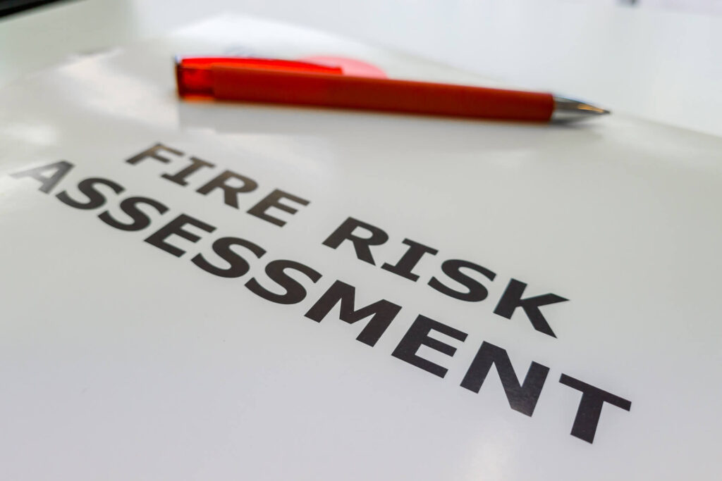 Fire Risk Assessment document with red pen—key component of Fire Safety Services for evaluating hazards and ensuring compliance in buildings and event venues.